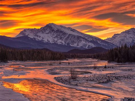 Sunset In Winter Mountains With Pine Trees Frozen River Snow Red Sky