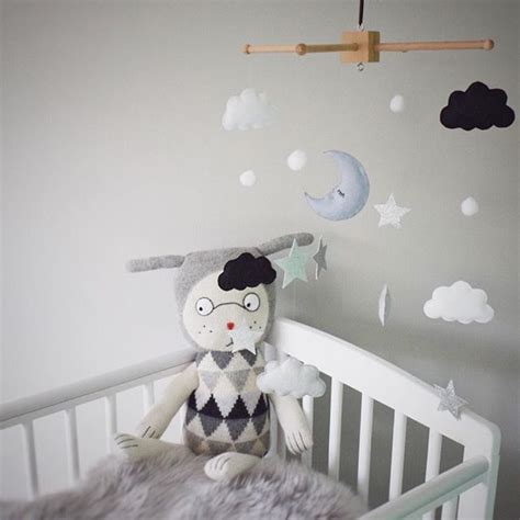 A Stuffed Animal Sitting On Top Of A Crib Next To A Wall With Clouds