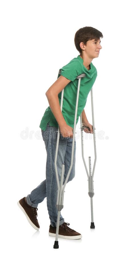 Teenage Boy With Injured Leg Using Crutches On White Background Stock