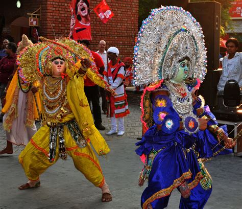 Two People Dressed In Colorful Costumes And Headdress
