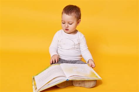 La Niña Pequeña Finge Leer Un Libro Mientras Está Sentada En El Piso
