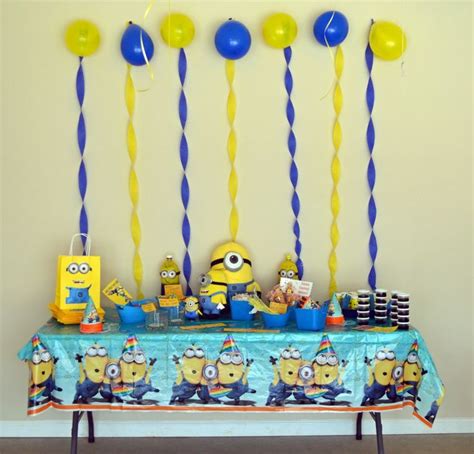 A Table Topped With Balloons And Minion Party Decorations On Top Of A