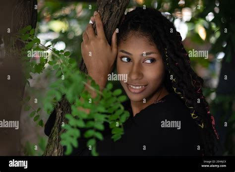 Portrait Of Attractive Afro Latina Woman With Dreadlocks Hugging A Tree