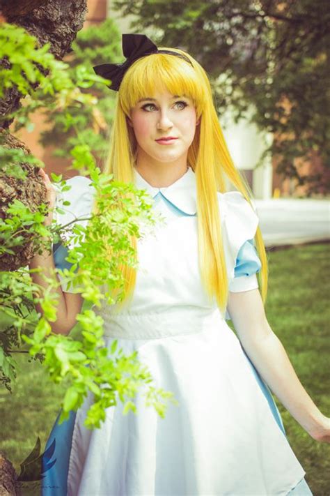 a woman with long blonde hair wearing a white dress and black cat ears standing next to a tree