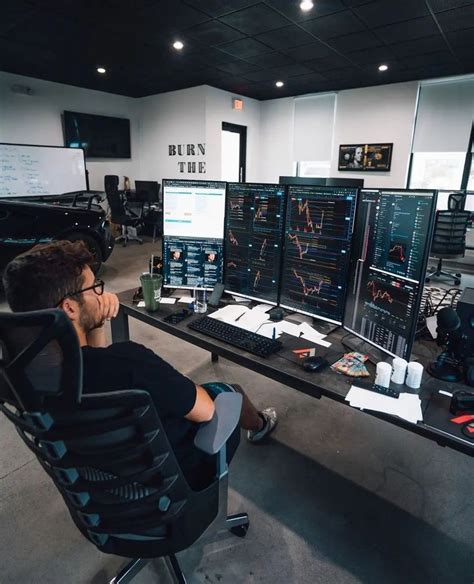 A Man Sitting At A Desk In Front Of Multiple Computer Monitors