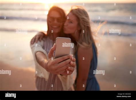 zwei freundinnen nehmen eine selfie am strand mit handy frauen am meer ufer bei sonnenuntergang