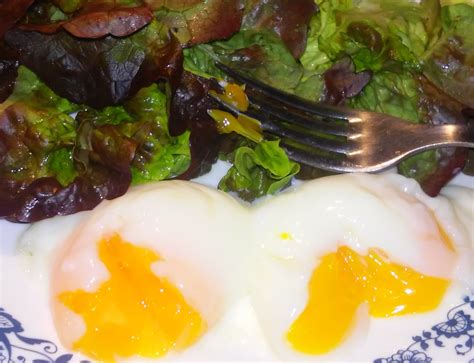 Two Fried Eggs On Top Of Lettuce With A Fork Next To The Salad