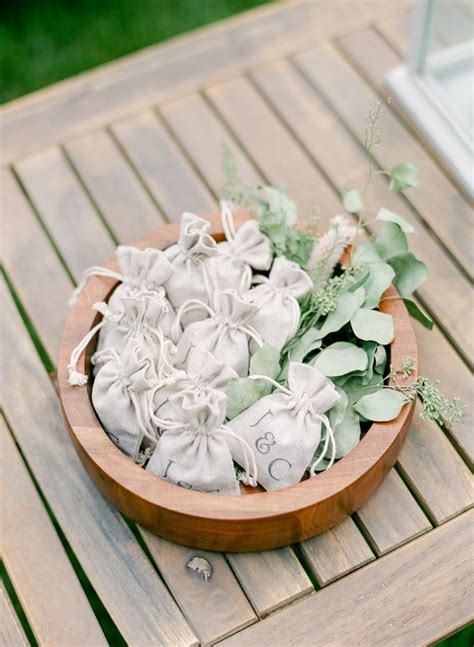 A Wooden Bowl Filled With Lots Of Small White Bags Next To Greenery On