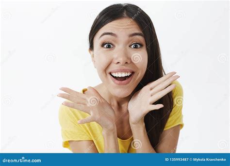 amused and excited happy enthusiastic woman with dark hair in yellow t shirt holding palms near