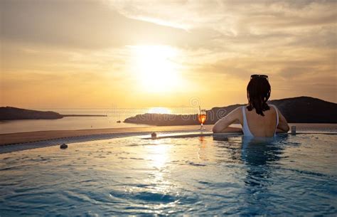 Woman In Infinity Swimming Pool At Golden Sunset Summer Vacation