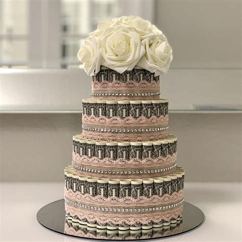 A Three Tiered Cake Decorated With Dollar Bills And White Flowers On A