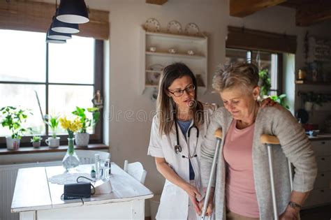 Healthcare Worker Or Caregiver Visiting Senior Woman Indoors At Home Helping Her To Walk Stock