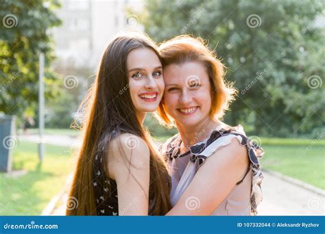 Closeup Portrait Of Adult Daughter And Mother Outdoors Pretty Brunette And Her Mom Are Looking