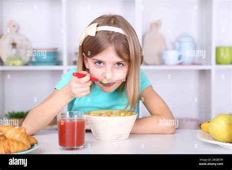 Beautiful Little Girl Eating Breakfast In Kitchen At Home Stock Photo