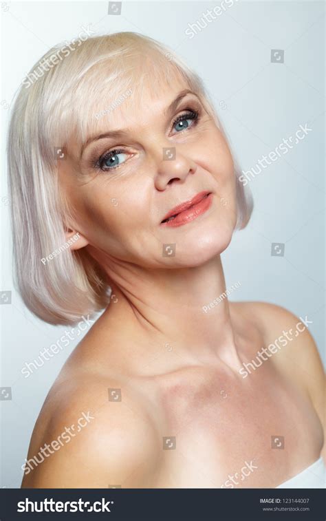 Side View Of A Nude Senior Lady Looking At Camera With A Charming Smile Stock Photo