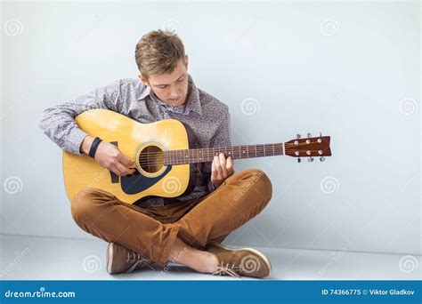 Portrait Of Handsome Man Playing Guitar Siting On Floor Stock Image
