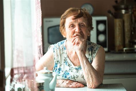 Portrait Of An Old Retired Woman Sitting At A Table Stock Image
