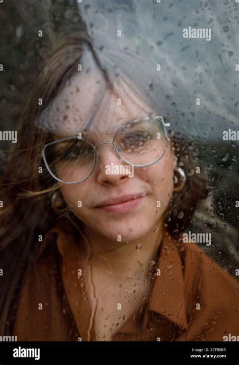 Portrait Of Beautiful Woman With Glasses Looking Out Of Wet Window On
