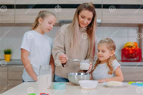 Mom Teaches Her Daughters To Cook Dough In The Kitchen Stock Image