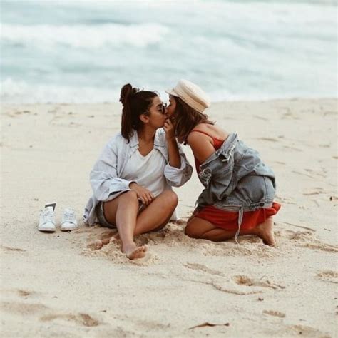 Two Women Sitting On The Beach Kissing Each Other