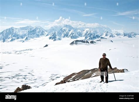 A Mountaineer Holding An Ice Axe Overlooks Mount Logan Canadas