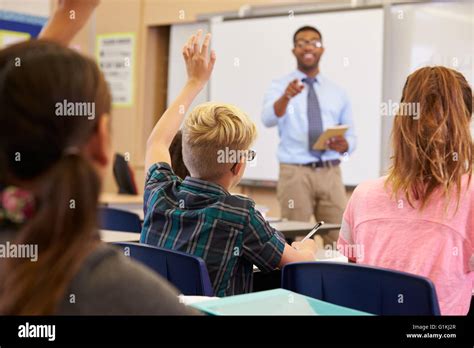 Kids Raising Hands To Answer In An Elementary School Class Stock Photo