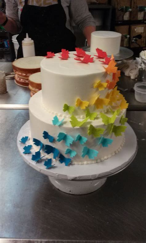 A Two Tier Buttercream Cake Covered With Fondant Butterflies