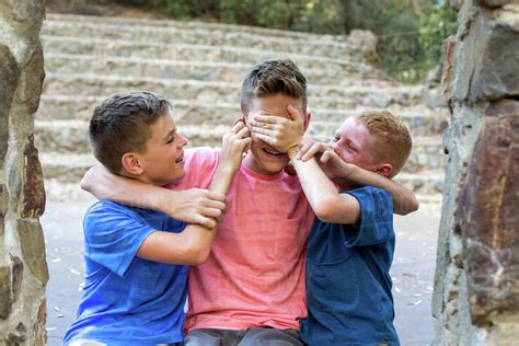 Two younger brothers gang up on older brother playfully - Stock Photo ...