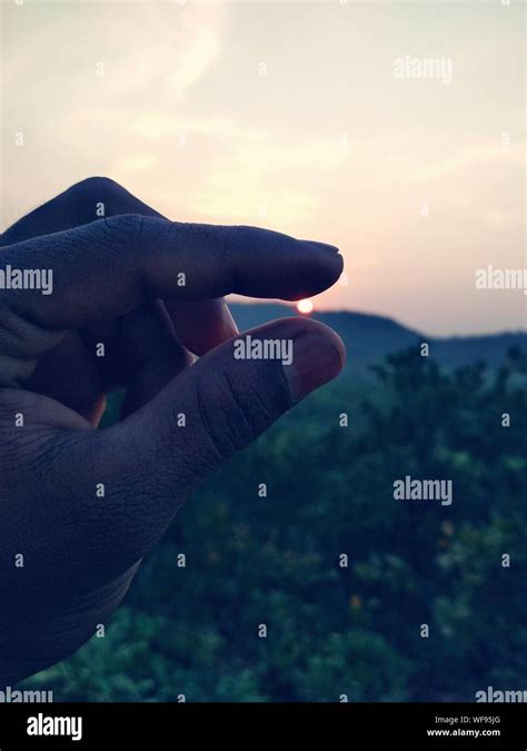Optical Illusion Of Hand Holding Sunset Stock Photo Alamy
