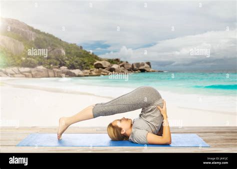 Woman Doing Yoga In Plow Pose On Beach Stock Photo Alamy