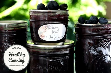 Jars Filled With Blueberry Jam Sitting On Top Of A Table Next To A Sign