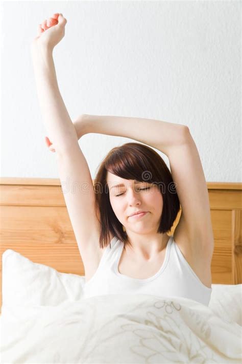 A Woman Laying In Bed With Her Arms Up And Head Resting On The Pillow Royalty Images