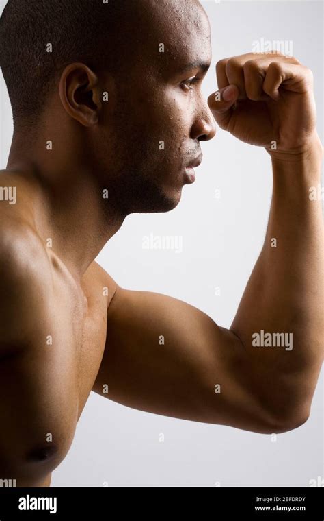 Profile View Of A Young Male Flexing His Left Bicep Muscle Stock Photo