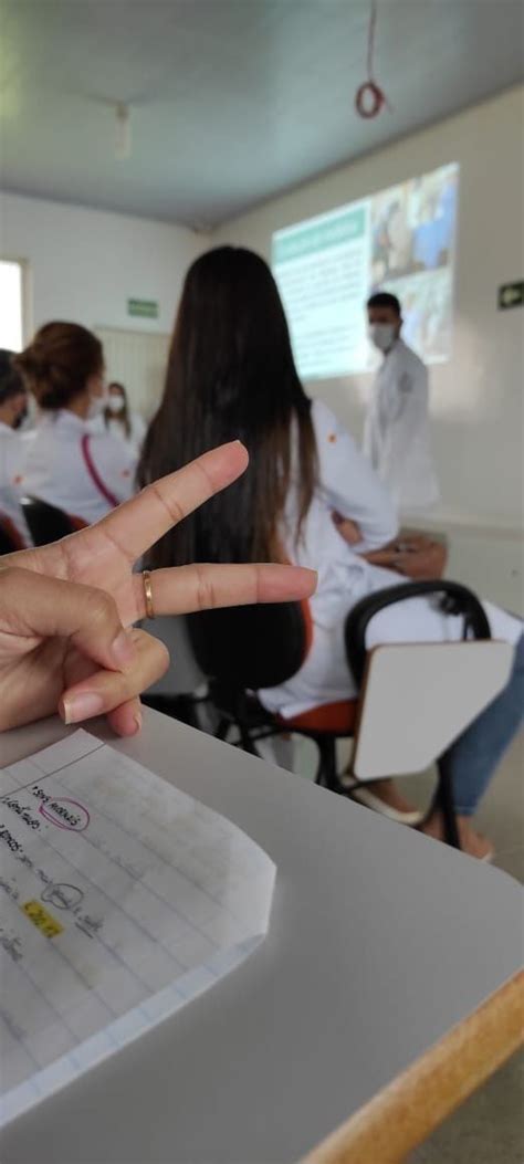 A Person Making A Peace Sign In Front Of Other People Sitting At Desks