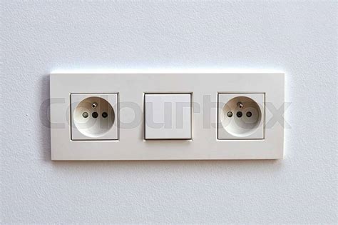 White Light Switch And Electrical Outlet In Front Of White Wall Stock