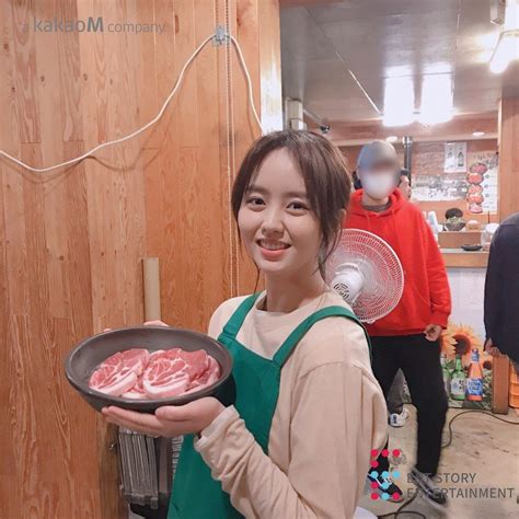 A Woman Holding A Pan With Raw Meat On It