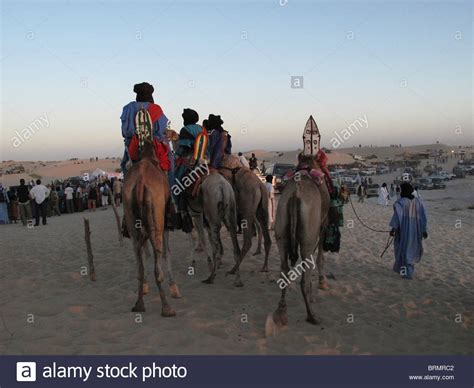 Tuareg Men On Camels Dressed In Traditional Robes Watching A