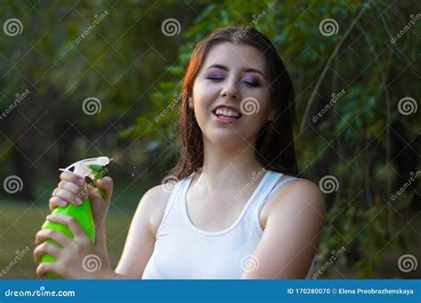 Young Woman Spraying Water On Herself From A Spray Bottle In A Summer