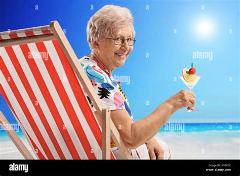 Ältere Frau bei einem Cocktail im Liegestuhl sitzen auf einem Strand