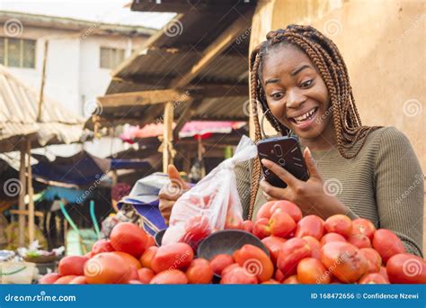 Beautiful Young African Woman In A Local African Market Viewing Content