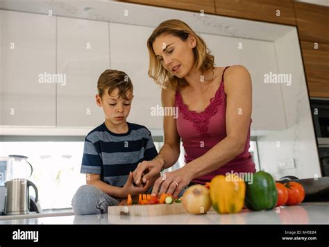 Mother Helping Son Cutting Fresh Vegetables In Kitchen Woman With
