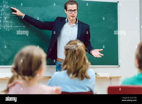 Teacher Standing In Front Of Students In School Class Explaining