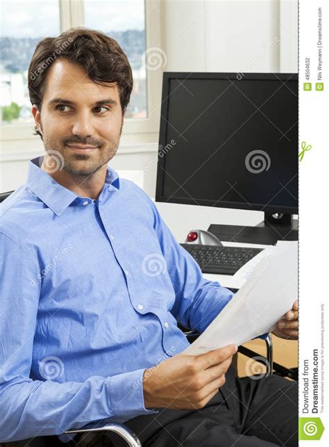 Young Handsome Manager Sitting At His Desk In The Office Stock Photo