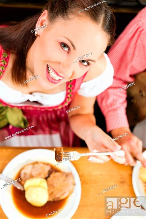 Inn Or Pub In Bavaria Couple In Traditional Tracht Drinking Beer And Eating Roast Pork With
