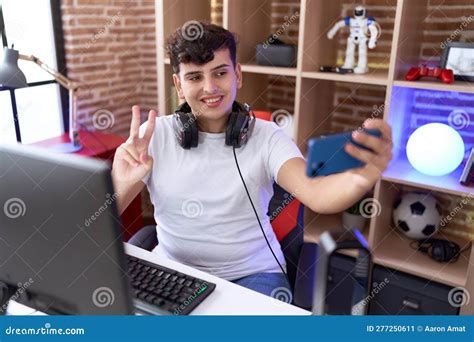non binary man streamer smiling confident make selfie by smartphone at gaming room stock image