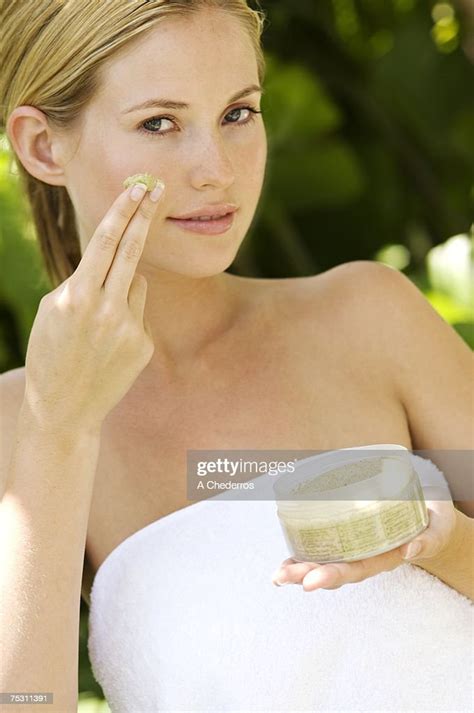 Young Woman Applying Face Scrub Cream On Her Face Outdoors High Res