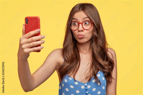 pretty girl takes selfie pouts lips at camera of cell phone makes video call flirts with