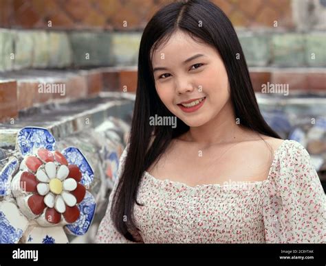 pretty thai girl with long hair smiles for the camera at bangkok s famous wat arun temple stock