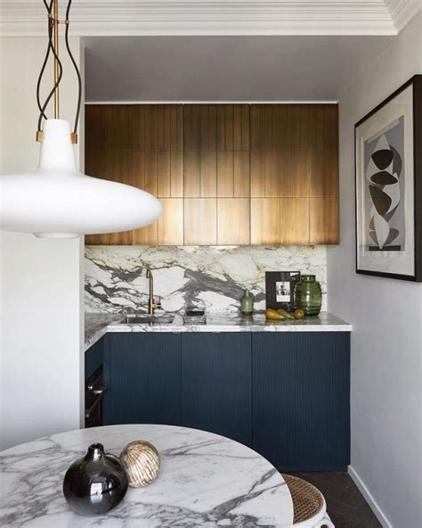 Natural light collides with the white upper cabinets, backsplash and counters, keeping the space bright. Small kitchen with dark blue lower cabinets and brass effect upper cabinet by patricé | Interior ...