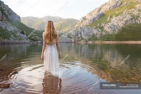 Backview Of Woman Standing In Mountain Lake In White Dress — Girl
